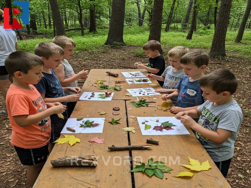 a-group-of-young-children-enthusiastically-participating-in-a-structured-nature-craft-activity-using-collected-leaves-and-sticks-to-create-art-demonstrating-fun-summer-
