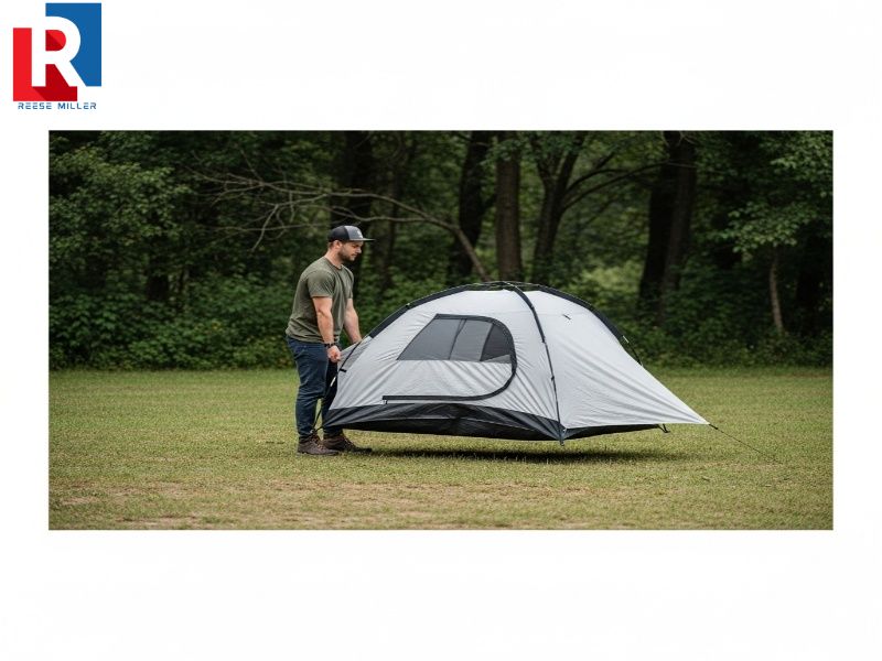 camper-easily-lifting-and-moving-a-fully-assembled-small-free-standing-tent-across-a-campsite