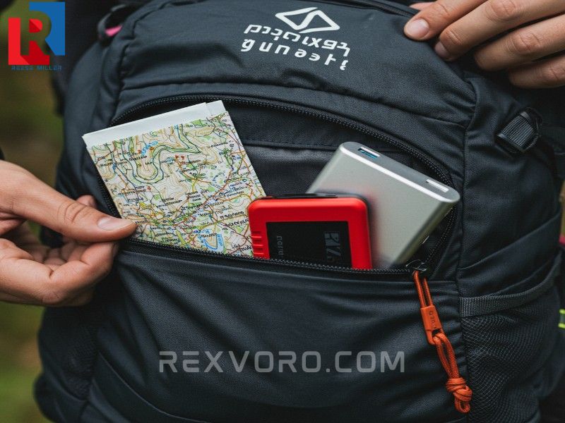 hand-zipping-a-backpack-pocket-containing-a-map-red-compass-and-power-bank-for-navigation
